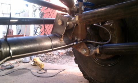 1990 Ford Bronco - Custom suspension work is underway on the rear axle, with various metal components and brake lines visible.