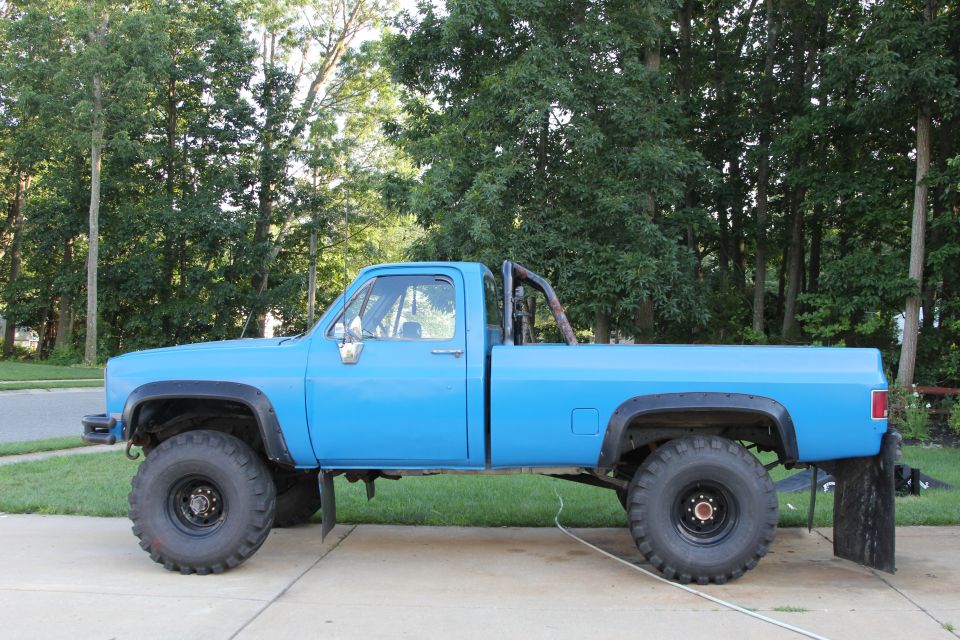 Side view of a blue 1978 Chevrolet C/K Pickup with large off-road tires and a roll bar