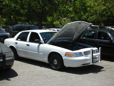 2004 Ford Crown Victoria - White 2004 Ford Crown Victoria police car with hood open, parked at an outdoor event.