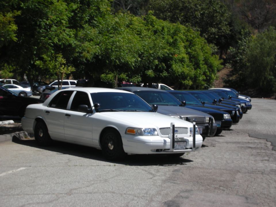 White 2004 Ford Crown Victoria police car, front quarter view, parked in a line