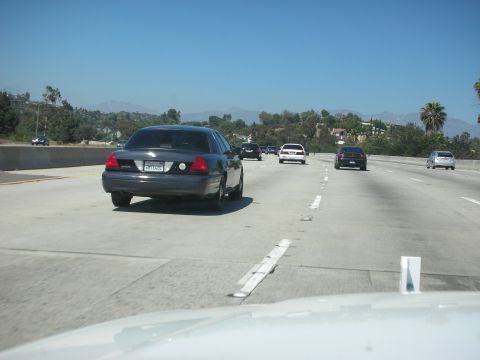 2004 Ford Crown Victoria - A dark sedan, identified as a 2004 Ford Crown Victoria, travels on a highway.