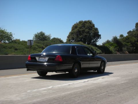 2004 Ford Crown Victoria - Rear view of a black 2004 Ford Crown Victoria sedan on the highway.