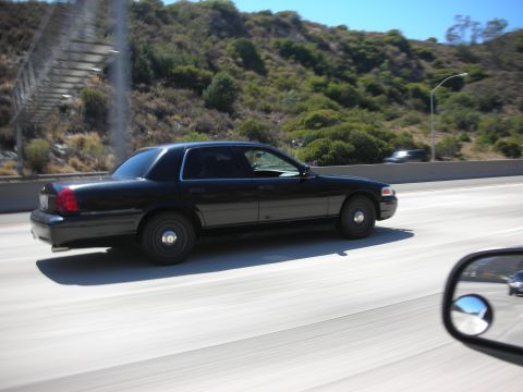 2004 Ford Crown Victoria - A black 2004 Ford Crown Victoria sedan is seen from the side on a highway.