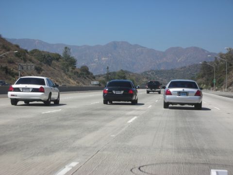 2004 Ford Crown Victoria - Traffic moves along a highway with a mountain range visible in the background.