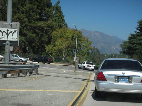 2004 Ford Crown Victoria - Silver 2004 Ford Crown Victoria seen from behind at an intersection with a white Crown Victoria in the distance.