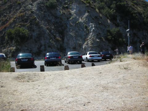 2004 Ford Crown Victoria - Several Ford Crown Victorias are parked in a lot near a rocky hillside.