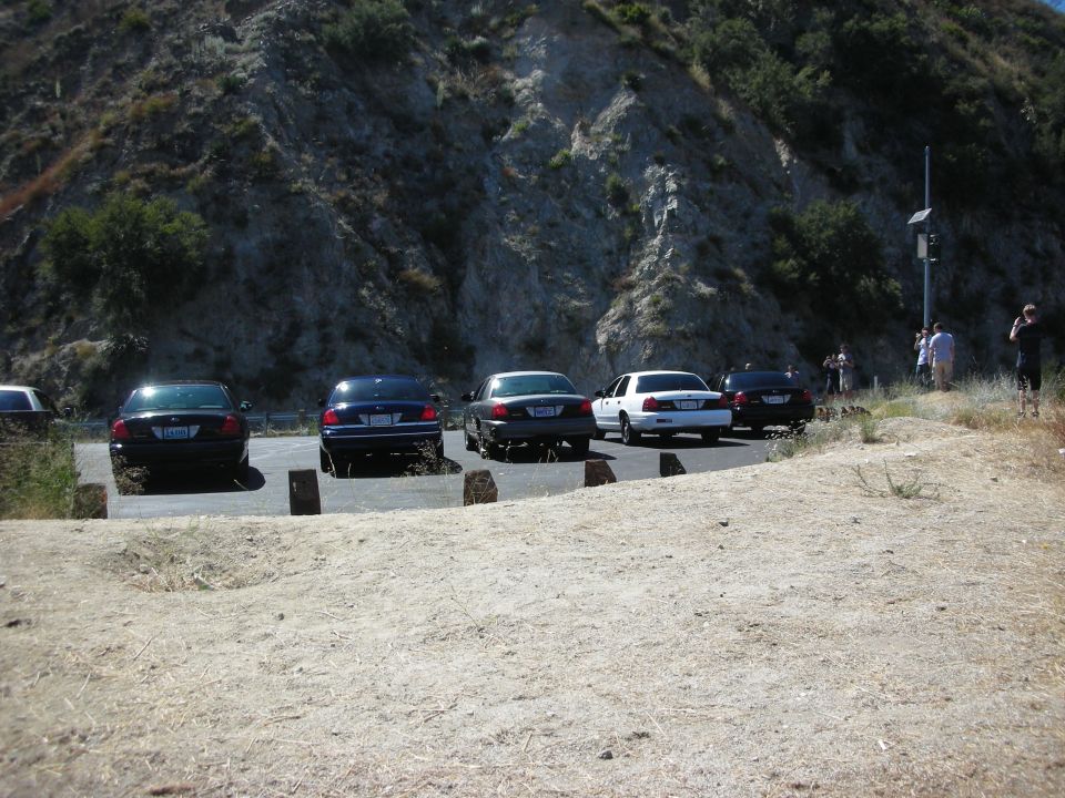 Four Ford Crown Victorias parked on a dirt lot with a rocky hillside behind them