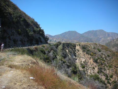 2004 Ford Crown Victoria - A scenic view of a mountain road with dry grass and sparse vegetation under a clear blue sky.