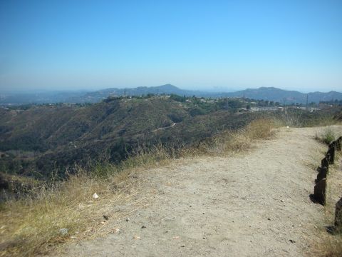 2004 Ford Crown Victoria - Hilly terrain with sparse vegetation and a hazy cityscape in the distance.