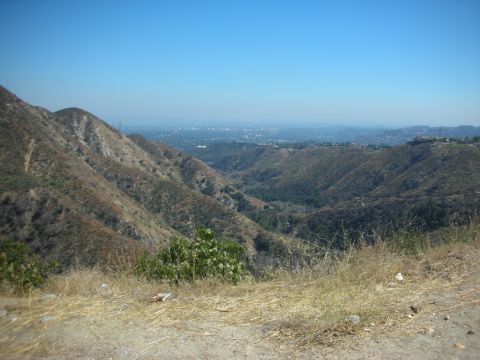 2004 Ford Crown Victoria - A wide shot captures a vast valley landscape with arid hillsides and a hazy urban sprawl in the distance.