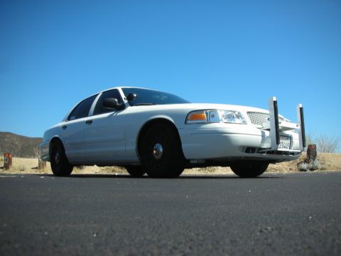 2004 Ford Crown Victoria - This sedan, possibly a 2004 Ford Crown Victoria, is parked outdoors under a bright blue sky.