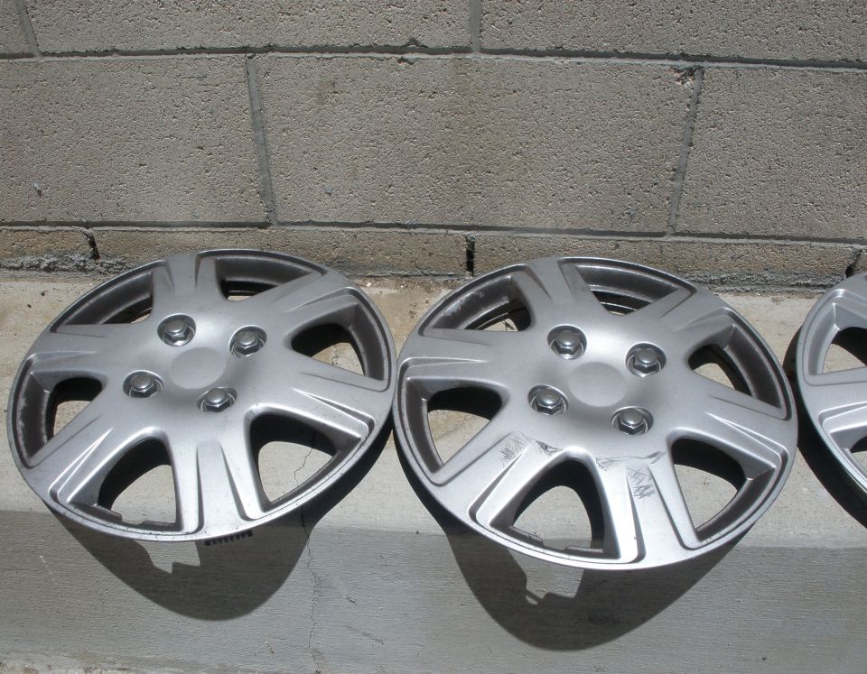 pair of silver hubcaps, one with scratches