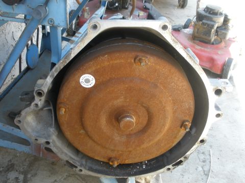 1995 Ford Thunderbird - A heavily rusted torque converter is visible within a transmission housing, with a lawnmower in the background.