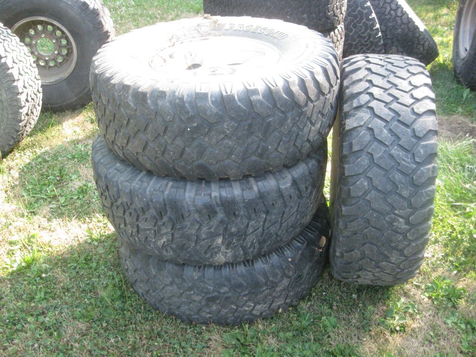 stack of four large off-road tires, one leaning against the stack