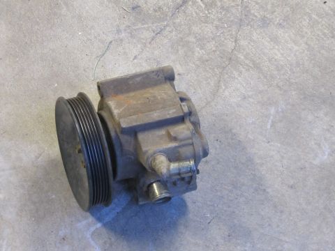 1995 Ford Bronco - A used power steering pump with its pulley is shown on a concrete floor.