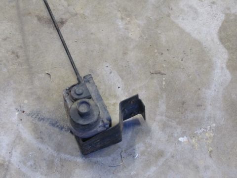 1995 Ford Bronco - A vacuum actuator assembly with a metal mounting bracket is shown on a concrete surface.