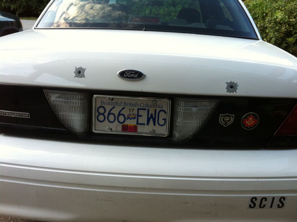 White 2005 Ford Crown Victoria rear with bullet holes and license plate 866 EWG