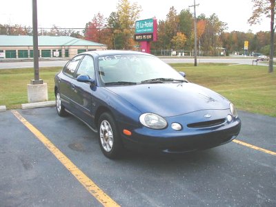 1997 Ford Taurus - Blue sedan parked in a lot with '96 Ford' written on the windshield.