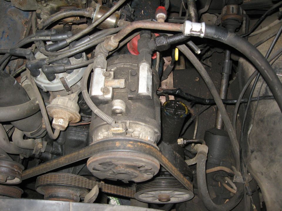 Engine bay with AC compressor, distributor, and belts visible