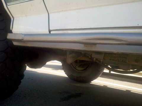1996 Ford Bronco - Side view of a white SUV aftermarket sliders and large off-road tires.