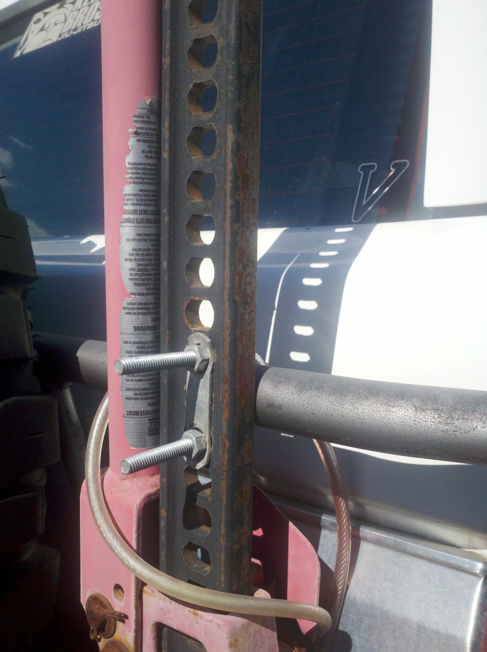 Close-up of a Hi-lift jack with bolts attached, mounted to a vehicle's exterior