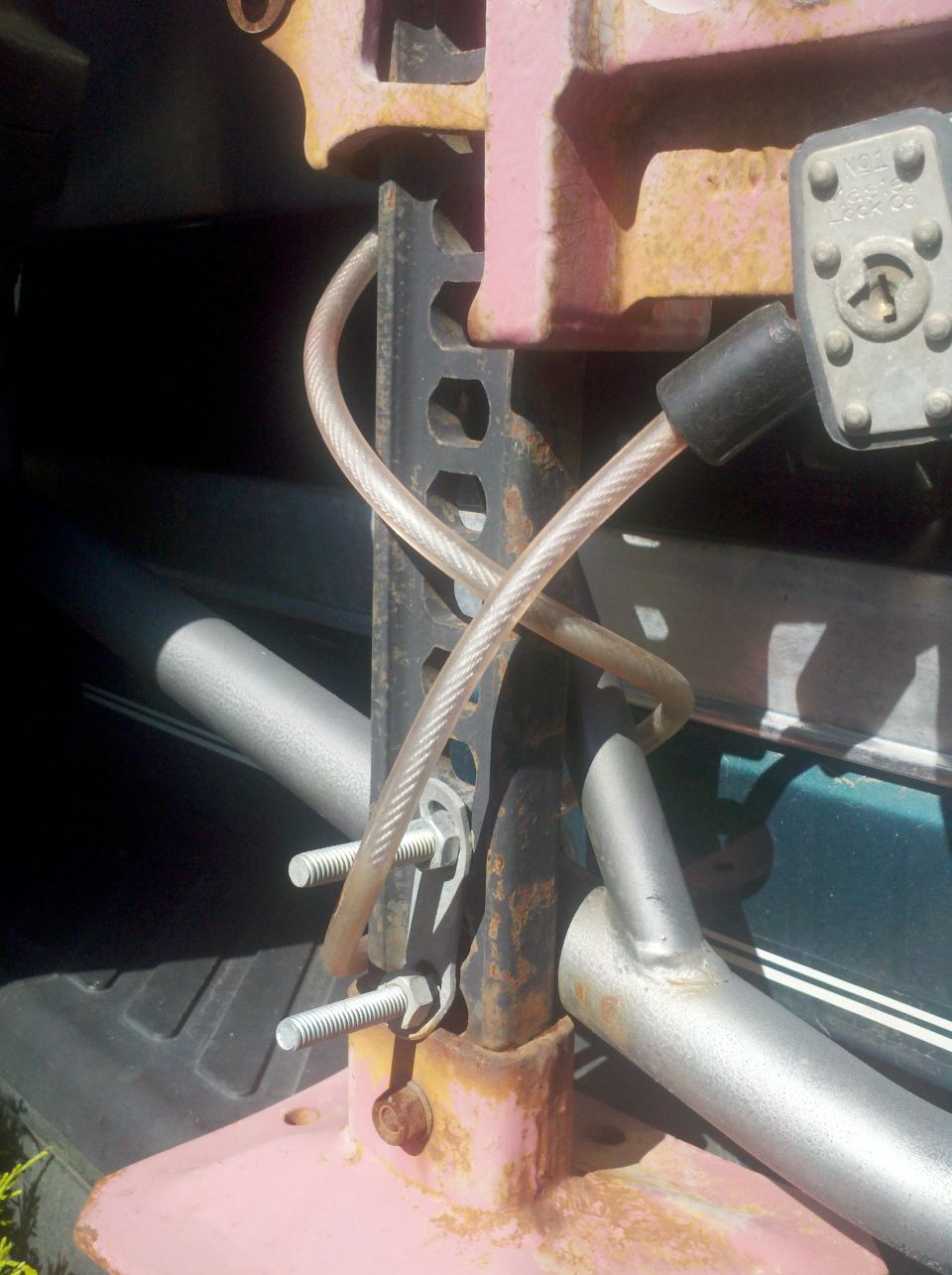 Close-up of a hi-lift jack secured with bolts and a cable lock inside a vehicle