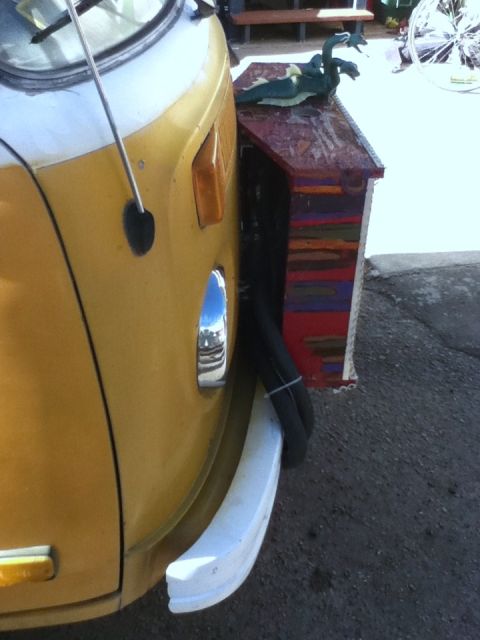 2006 Ford E350 - Front corner of a yellow and white van with a custom-painted wooden box mounted to the side.