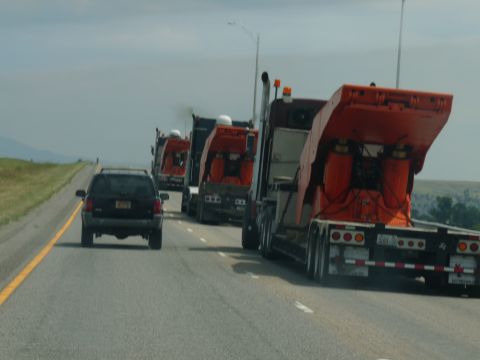 2006 Ford E350 - Multiple semi-trucks with orange trailers are on the highway, with a black SUV in front.