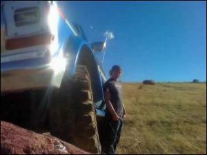 1996 Ford Bronco - A person stands next to a vehicle's large off-road tire and fender, with a bright blue sky overhead.