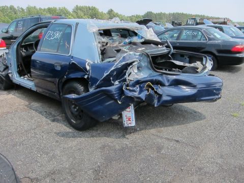 1991 Ford LTD Crown Victoria - This severely damaged sedan sits in a lot with other vehicles. The rear of the car is completely mangled.