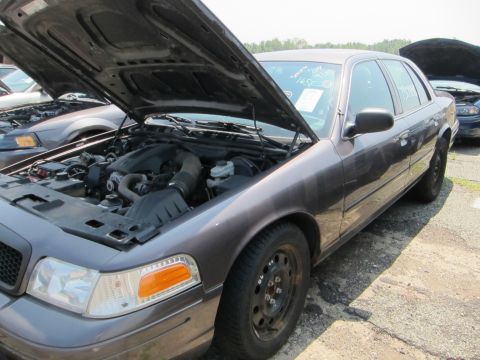 1991 Ford LTD Crown Victoria - Engine bay of a gray sedan is visible with the hood raised, parked outdoors with another car nearby.
