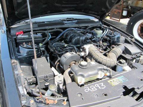 1991 Ford LTD Crown Victoria - The engine bay of a vehicle is shown with the hood open, revealing various components and some handwritten numbers.