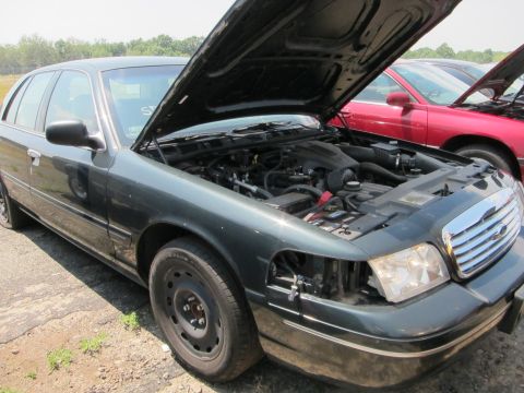 1991 Ford LTD Crown Victoria - Dark green sedan with hood open, parked next to a red car.