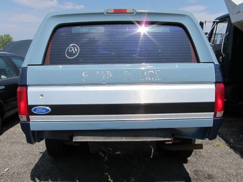 1991 Ford LTD Crown Victoria - A light blue and dark blue Ford pickup truck with a camper shell is seen from the rear, with a "91" sticker on the window.