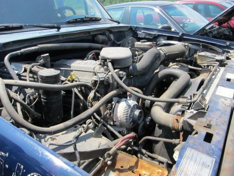 1991 Ford LTD Crown Victoria - The engine compartment of a blue vehicle is shown, with other vehicles in the background.