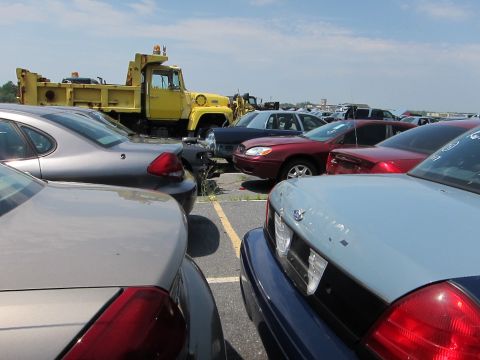 1991 Ford LTD Crown Victoria - A collection of vehicles, including a yellow dump truck and various sedans, are parked in an open lot.