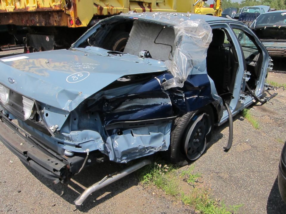 Heavily damaged 1991 Ford Crown Victoria LTD, 3q-front view, light blue with dark blue accents. Number 85 visible on hood