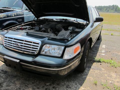 1991 Ford LTD Crown Victoria - A dark green Ford Crown Victoria is parked outdoors with its hood open, revealing the engine compartment.