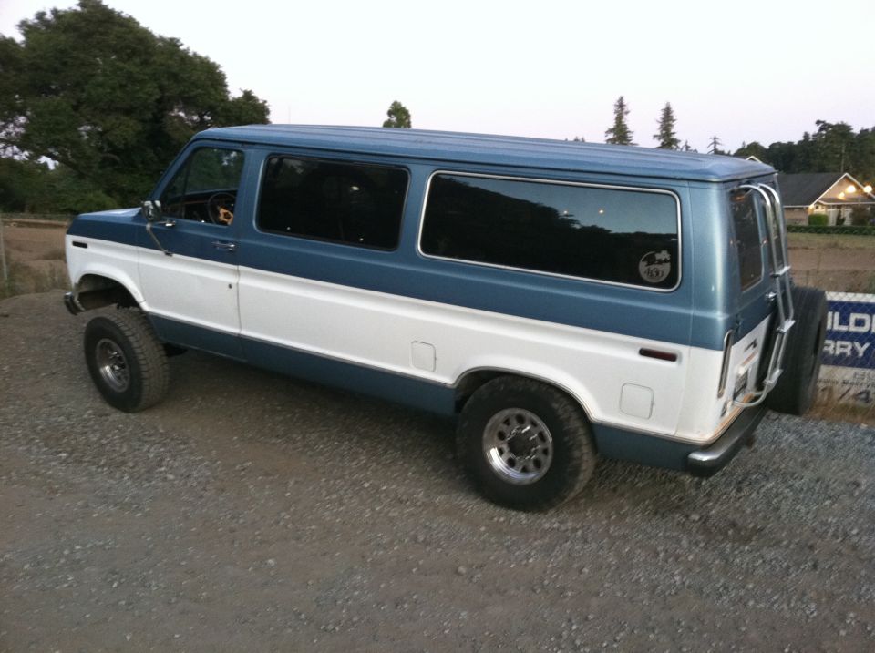 Blue and white van with lifted suspension and spare tire on back