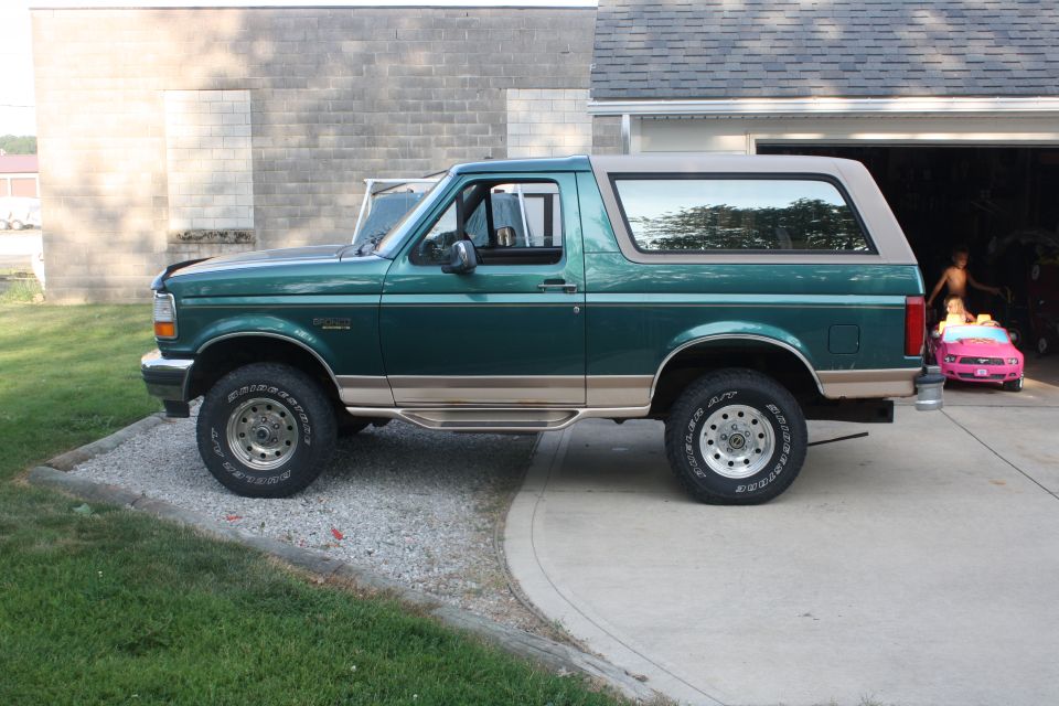 Green 1996 Ford Bronco parked on a driveway, side view