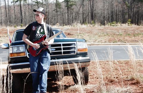 1993 Ford Bronco - A young man poses with his electric guitar next to a Ford F-Series pickup truck.
