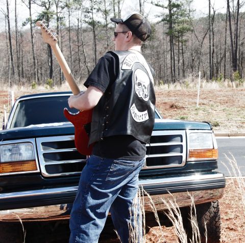 1993 Ford Bronco - A man with a guitar stands in front of a green truck.