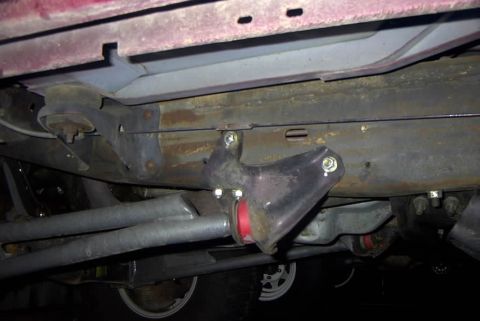 1994 Ford Bronco - Underside view of a vehicle's suspension component with a red bushing.