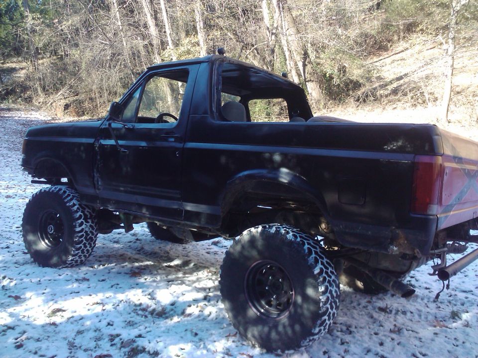 Black lifted 1989 Ford Bronco with removable top in snowy woods