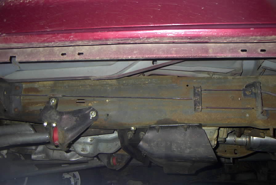 Underbody view of red vehicle showing suspension components and frame