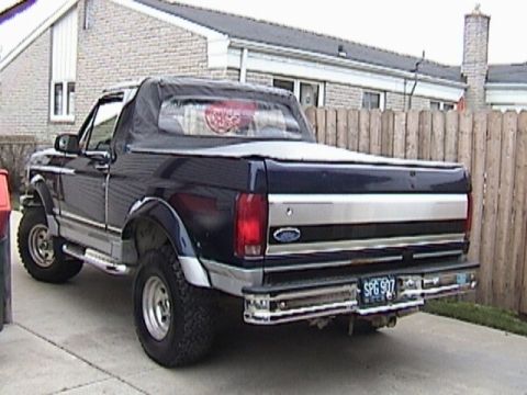 1995 Ford Bronco - Rear view of a 1995 Ford Bronco with a soft top and chrome bumper.