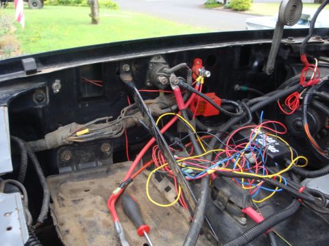 1989 Ford Bronco - Close-up view of the complex wiring and components in a vehicle's engine bay, including the battery tray and starter solenoid.