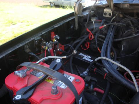 1989 Ford Bronco - Close-up view of a vehicle's engine bay, a red battery and various wiring components.