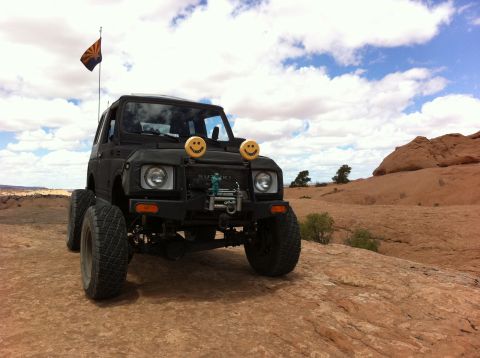 1987 Suzuki Samurai - Suzuki Samurai with smiley face headlights and Arizona flag on a rocky trail.