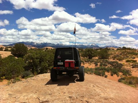 1987 Suzuki Samurai - This 1987 Suzuki Samurai is parked on a rock overlooking a desert landscape with snow-capped mountains in the distance.